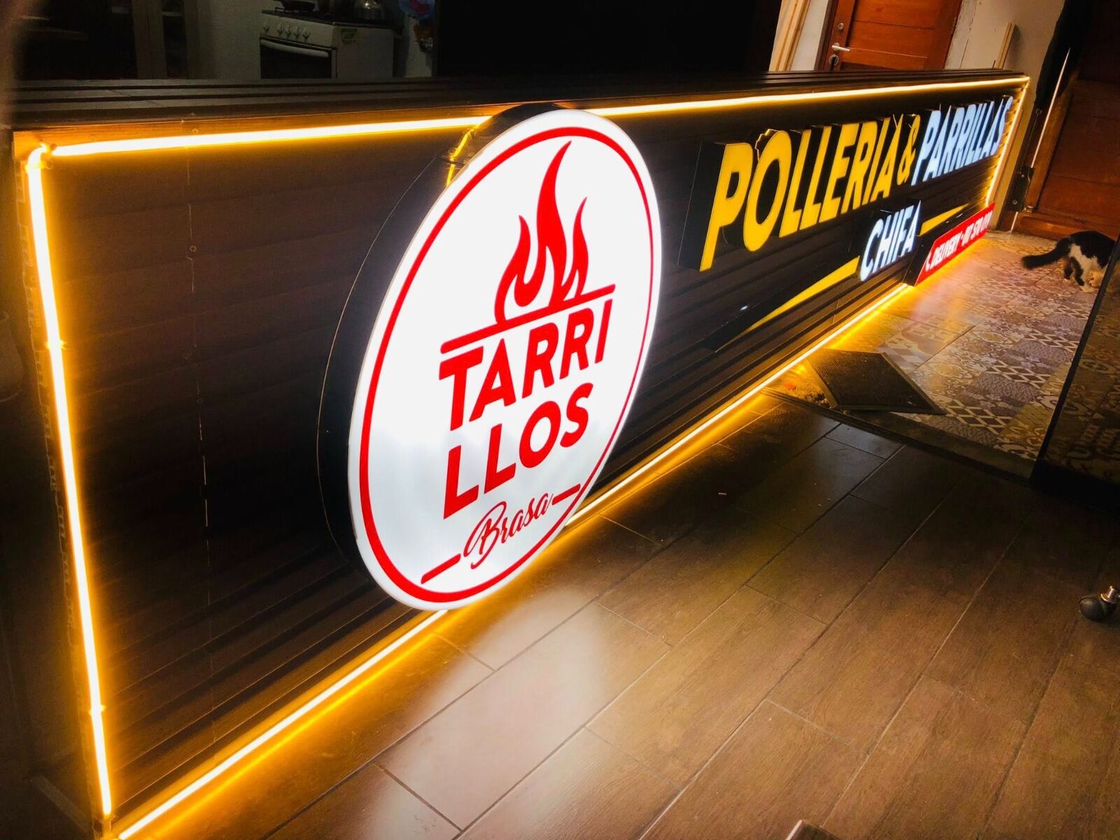 Letrero en alto relieve real para pollería y parrillas con logo circular volumétrico e iluminación LED ámbar.